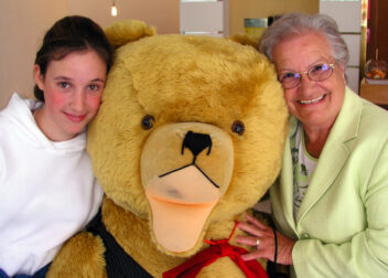 Junges Mädchen und ihre Oma posieren mit Riesenteddy